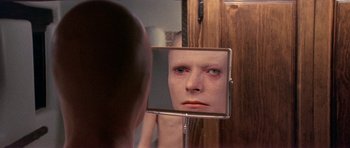 Movie still from “The Man Who Fell to Earth” (1976), directed by Nicolas Roeg – A man looking at himself in the mirror; Close Up shot, Over the shoulder angle