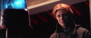 Movie still from “The Man Who Fell to Earth” (1976), directed by Nicolas Roeg – A man with red hair is looking at the camera; Close Up shot, Over the shoulder angle