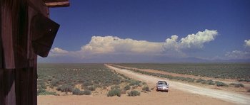Movie still from “The Man Who Fell to Earth” (1976), directed by Nicolas Roeg – A car is parked on the side of a dirt road in the desert; Extreme Wide shot, High angle