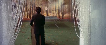 Movie still from “The Man Who Fell to Earth” (1976), directed by Nicolas Roeg – A man standing in front of a ping pong table in the woods; Wide shot, High angle