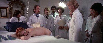 Movie still from “The Man Who Fell to Earth” (1976), directed by Nicolas Roeg – A group of doctors stand in front of a naked man; Medium shot, Low angle