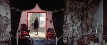 Movie still from “The Man Who Fell to Earth” (1976), directed by Nicolas Roeg – A woman is walking through a doorway to a living room; Wide shot, Over the shoulder angle