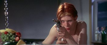 Movie still from “The Man Who Fell to Earth” (1976), directed by Nicolas Roeg – A woman holding a gun in her hands; Close Up shot, Low angle