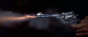 Movie still from “The Man Who Fell to Earth” (1976), directed by Nicolas Roeg – A gun is being fired in the dark; Extreme Close Up shot, High angle