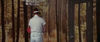 Movie still from “The Man Who Fell to Earth” (1976), directed by Nicolas Roeg – A man standing in front of a painting of a forest; Medium shot, Over the shoulder angle