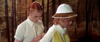 Movie still from “The Man Who Fell to Earth” (1976), directed by Nicolas Roeg – A woman wearing a white hat is looking at a cell phone; Close Up shot, Over the shoulder angle