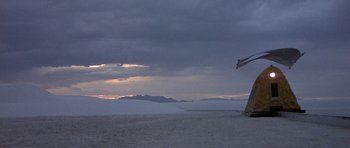 Movie still from “The Man Who Fell to Earth” (1976), directed by Nicolas Roeg – The sun is setting on a beach with mountains in the background; Extreme Wide shot, Low angle