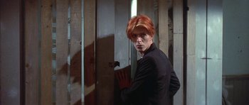 Movie still from “The Man Who Fell to Earth” (1976), directed by Nicolas Roeg – A man with red hair standing next to a wall; Medium shot, Low angle