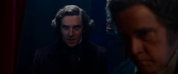 Movie still from “The Man Who Invented Christmas” (2017), directed by Bharat Nalluri – A man in a suit and tie looking at the camera; Close Up shot, Over the shoulder angle