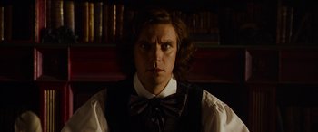 Movie still from “The Man Who Invented Christmas” (2017), directed by Bharat Nalluri – A man in a vest and bow tie stares at the camera; Close Up shot, Low angle