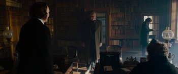 Movie still from “The Man Who Invented Christmas” (2017), directed by Bharat Nalluri – A man standing in front of a book case; Wide shot, Low angle