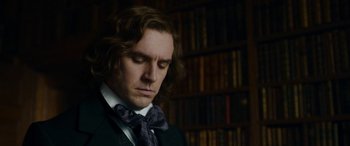 Movie still from “The Man Who Invented Christmas” (2017), directed by Bharat Nalluri – A man with long hair wearing a suit and a bow tie; Close Up shot, Over the shoulder angle
