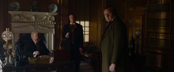 Movie still from “The Man Who Invented Christmas” (2017), directed by Bharat Nalluri – Two men standing in a room next to each other; Medium shot, Low angle