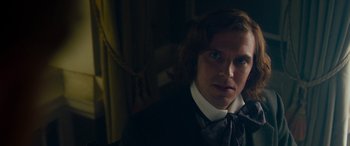 Movie still from “The Man Who Invented Christmas” (2017), directed by Bharat Nalluri – A man with long hair wearing a suit and tie; Close Up shot, Over the shoulder angle