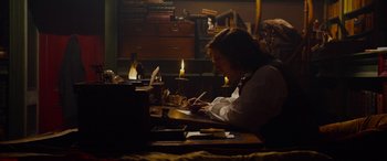 Movie still from “The Man Who Invented Christmas” (2017), directed by Bharat Nalluri – A person sitting at a desk writing on a paper; Medium shot, High angle