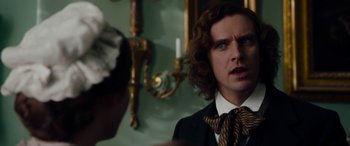 Movie still from “The Man Who Invented Christmas” (2017), directed by Bharat Nalluri – A man in a suit and tie looking at the camera; Close Up shot, Over the shoulder angle