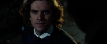 Movie still from “The Man Who Invented Christmas” (2017), directed by Bharat Nalluri – A person wearing a suit and bow tie; Close Up shot, Over the shoulder angle