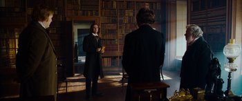 Movie still from “The Man Who Invented Christmas” (2017), directed by Bharat Nalluri – A man in a suit stands in front of another man in a black suit; Medium shot, Over the shoulder angle