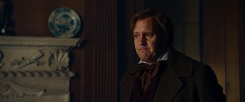 Movie still from “The Man Who Invented Christmas” (2017), directed by Bharat Nalluri – A man in a suit and bow tie looking to his left; Close Up shot, Over the shoulder angle