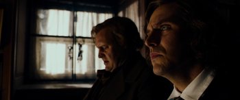 Movie still from “The Man Who Invented Christmas” (2017), directed by Bharat Nalluri – Two men are standing side by side in front of a window; Close Up shot, Low angle