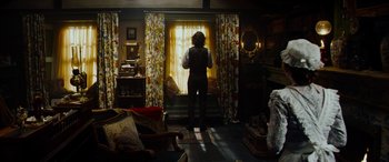 Movie still from “The Man Who Invented Christmas” (2017), directed by Bharat Nalluri – A man standing in front of a window in a living room; Wide shot, High angle