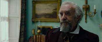 Movie still from “The Man Who Invented Christmas” (2017), directed by Bharat Nalluri – An old man with a beard and a long white beard wearing a suit; Close Up shot, Over the shoulder angle