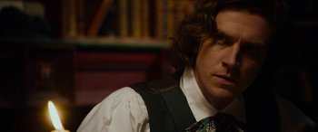 Movie still from “The Man Who Invented Christmas” (2017), directed by Bharat Nalluri – A man with curly brown hair wearing a vest and tie; Close Up shot, Over the shoulder angle