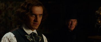 Movie still from “The Man Who Invented Christmas” (2017), directed by Bharat Nalluri – A person wearing a suit and a tie; Close Up shot, Over the shoulder angle