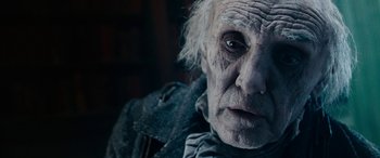 Movie still from “The Man Who Invented Christmas” (2017), directed by Bharat Nalluri – An old man with white hair and blue eyes stares into the camera; Close Up shot, Over the shoulder angle