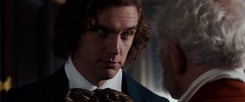 Movie still from “The Man Who Invented Christmas” (2017), directed by Bharat Nalluri – A person wearing a suit and a tie; Close Up shot, Over the shoulder angle