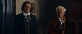 Movie still from “The Man Who Invented Christmas” (2017), directed by Bharat Nalluri – Two people standing next to each other in a room; Medium shot, Over the shoulder angle