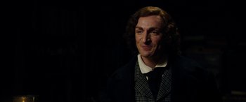 Movie still from “The Man Who Invented Christmas” (2017), directed by Bharat Nalluri – A man with long hair wearing a suit and tie; Close Up shot, Over the shoulder angle