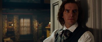 Movie still from “The Man Who Invented Christmas” (2017), directed by Bharat Nalluri – A person with long hair wearing a tie; Close Up shot, Over the shoulder angle