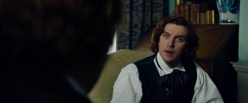 Movie still from “The Man Who Invented Christmas” (2017), directed by Bharat Nalluri – A man in a vest and tie sitting in a chair; Close Up shot, Over the shoulder angle