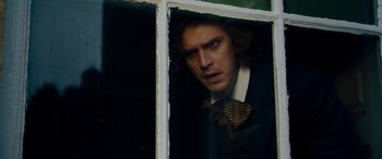 Movie still from “The Man Who Invented Christmas” (2017), directed by Bharat Nalluri – A man in a suit and tie looking out of a window; Close Up shot, Over the shoulder angle