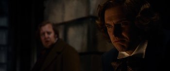 Movie still from “The Man Who Invented Christmas” (2017), directed by Bharat Nalluri – A man in a suit and tie looking at the camera; Close Up shot, Over the shoulder angle