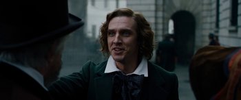 Movie still from “The Man Who Invented Christmas” (2017), directed by Bharat Nalluri – A person wearing a suit and tie; Close Up shot, Over the shoulder angle