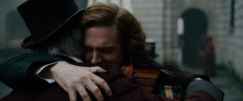 Movie still from “The Man Who Invented Christmas” (2017), directed by Bharat Nalluri – A man hugging another man with his arms wrapped around him; Close Up shot, Over the shoulder angle