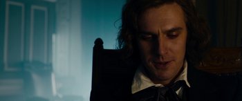 Movie still from “The Man Who Invented Christmas” (2017), directed by Bharat Nalluri – A person sitting in a chair; Close Up shot, Over the shoulder angle