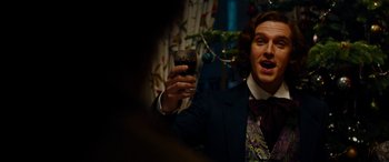 Movie still from “The Man Who Invented Christmas” (2017), directed by Bharat Nalluri – A man in a suit holding a glass of wine; Medium shot, Low angle