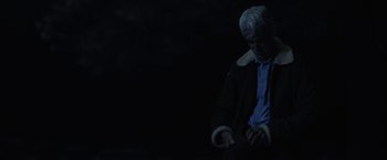 Movie still from “The Man Who Killed Hitler and Then the Bigfoot” (2018), directed by Robert D. Krzykowski – An older man looking at his watch in the dark; Medium shot, Low angle
