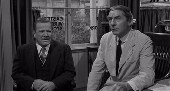 Movie still from “The Man Who Shot Liberty Valance” (1962), directed by John Ford – A black and white photo of two men sitting next to each other; Medium shot, Over the shoulder angle