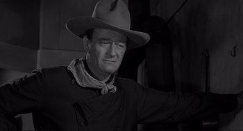 Movie still from “The Man Who Shot Liberty Valance” (1962), directed by John Ford – A black and white photo of a man wearing a cowboy hat; Medium shot, Over the shoulder angle