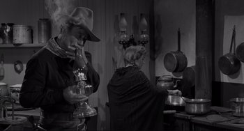 Movie still from “The Man Who Shot Liberty Valance” (1962), directed by John Ford – A man and a woman are standing in front of a stove; Medium shot, High angle