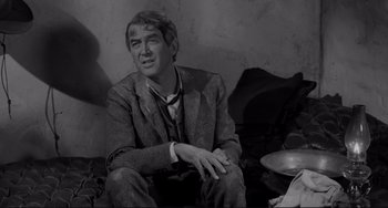 Movie still from “The Man Who Shot Liberty Valance” (1962), directed by John Ford – A black and white photo of a man sitting on the ground; Close Up shot, Over the shoulder angle