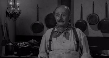 Movie still from “The Man Who Shot Liberty Valance” (1962), directed by John Ford – An older man in a kitchen wearing an apron; Medium shot, High angle