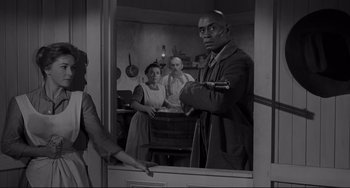 Movie still from “The Man Who Shot Liberty Valance” (1962), directed by John Ford – A group of people standing in a room; Medium shot, Over the shoulder angle