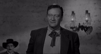 Movie still from “The Man Who Shot Liberty Valance” (1962), directed by John Ford – A black and white photo of a man wearing a suit and tie; Medium shot, Low angle