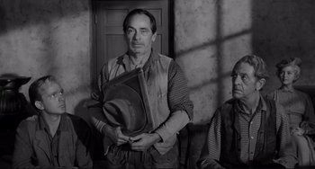 Movie still from “The Man Who Shot Liberty Valance” (1962), directed by John Ford – A black and white photo of a man holding a hat; Medium shot, Low angle