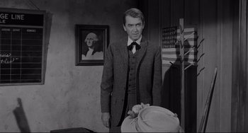 Movie still from “The Man Who Shot Liberty Valance” (1962), directed by John Ford – A black and white photo of a man in a suit and tie; Medium shot, Over the shoulder angle